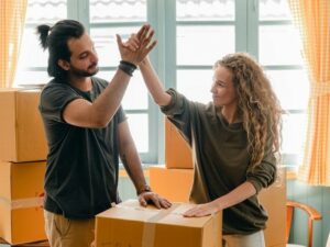 A guy and girl cheering themselves after packing the boxes